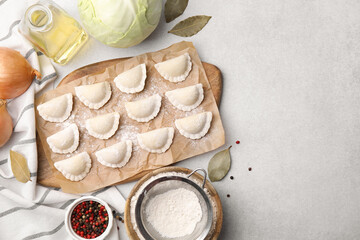 Raw dumplings (varenyky) with tasty filling and ingredients on light grey table, flat lay. Space...