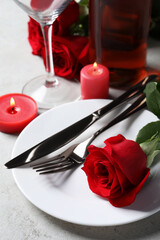 Fototapeta na wymiar Beautiful place setting with dishware, candles and rose for romantic dinner on light table, closeup