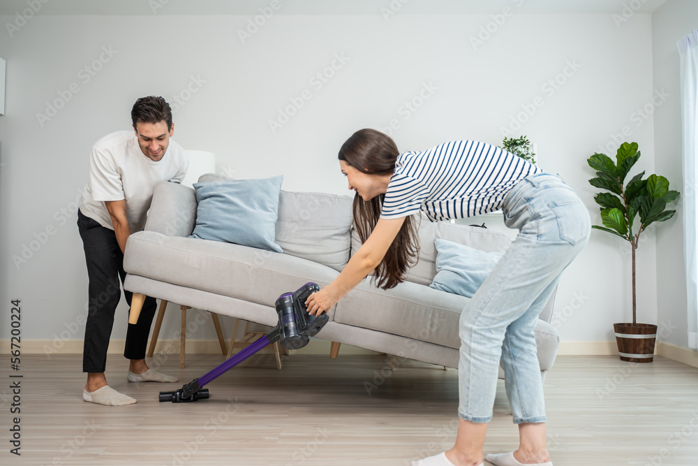 Sticker caucasian young man and woman cleaning living room together at home.