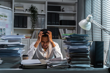 Frustrated Asian young businessman worker working on table in office.  - obrazy, fototapety, plakaty