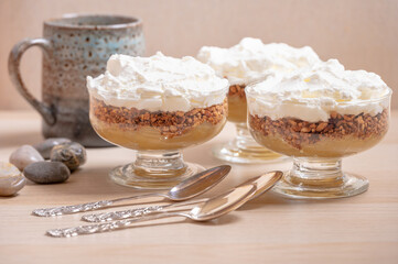 Three individual servings of an apple compote dessert and three silver spoons.