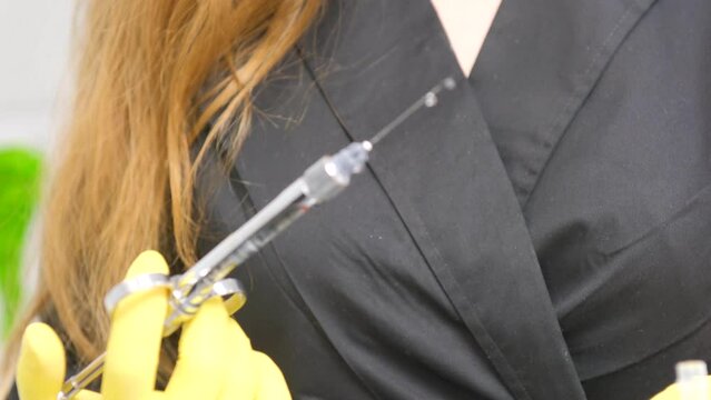 Woman holding medical injection syringe in her outstretched hand towards the camera. Selective focus, copy space Blue glove decoration on the hand of a female