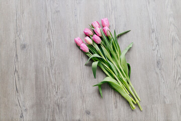 Pink tulips lie on a wooden surface. Spring background with flowers. Valentine's day card.