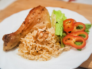 Delicious chicken drumstick with rice and vegetables on the plate