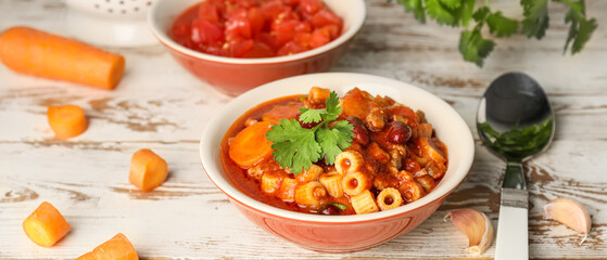 Bowl with tasty pasta and beans on white wooden table