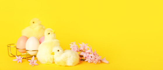 Cute chickens, spring flowers and Easter eggs on yellow background with space for text