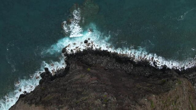 Ocean waves crash on Molokai, Hawaii shoreline. Halawa Valley tropical enviroment establishing shot. Aerial pull back reveal with tilt up.