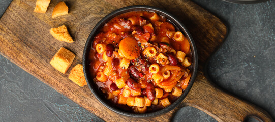 Bowl with tasty pasta and beans on dark background, top view