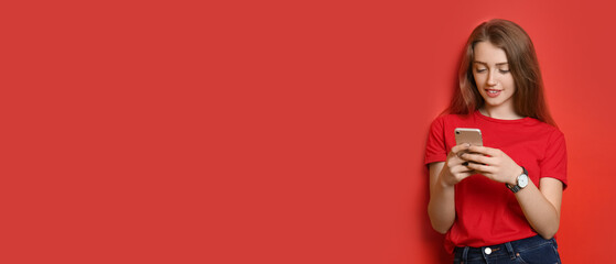 Beautiful young woman with mobile phone on red background with space for text