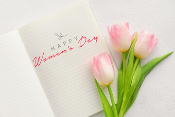 Notebook with text HAPPY WOMEN'S DAY and tulips on light background