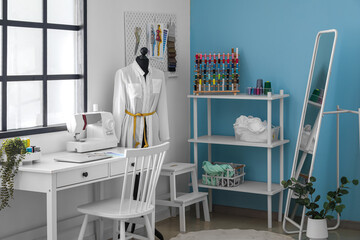 Interior of stylish atelier with workplace, mannequin and shelving unit