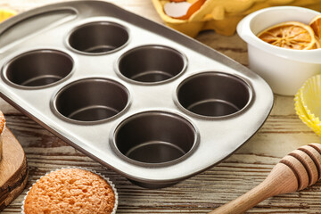 Muffin tray on light wooden table, closeup