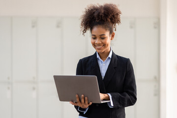 Portrait of attractive cheerful skilled business girl using laptop winking in office over bright background