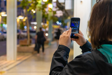 The girl shoots the evening city with her phone