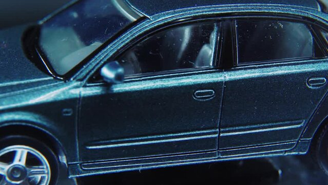 A tiny model metal sample car on a rotating stand with studio lights, macro close up shot, 4K video, silver wheels, black tires, doors and windows