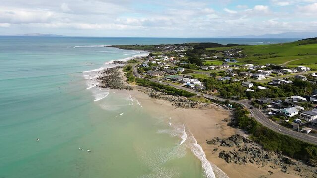 Aerial view of beautiful Riverton coastline in New Zealand on a sunny day. Surfers and cars appearing.