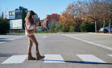 Child looking at the cellphone while crossing crosswalk