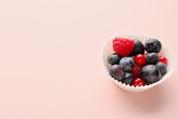 Paper baking cup with fresh berries on pink background
