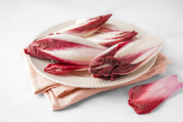 Plate with fresh red endive on light background