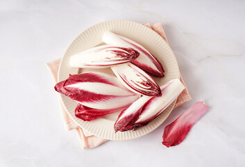 Plate with fresh red endive on light background
