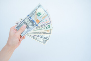 Cropped shot of someone hand showing various American dollar banknotes with isolated white background.