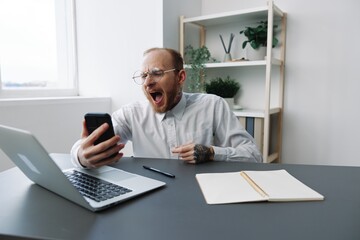 Fototapeta premium A man in a wheelchair a businessman with tattoos in the office works, talking on the phone screaming and angry, integration into society, the concept of working a person with disabilities