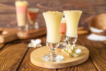 Board with shots of delicious vanilla pudding on wooden table, closeup