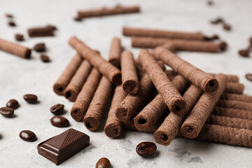 Delicious rolled wafer cookies with coffee beans and chocolate pieces on grunge background