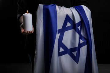 Jewish woman with flag of Israel and burning candle on dark background, closeup. International...