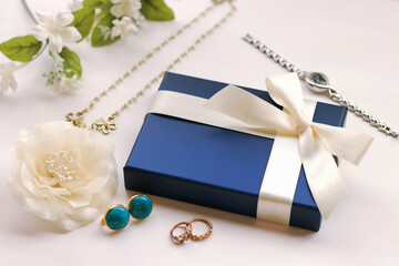 白いリボンがかかった青いギフトボックスとアクセサリーのプレゼントイメージ