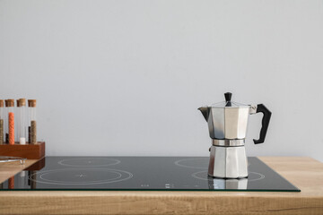Geyser coffee maker on electric stove in kitchen near grey wall