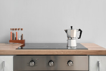 Geyser coffee maker on electric stove in kitchen near grey wall