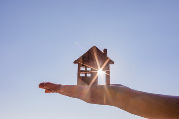 estate sold agent hand holds wooden house against the sun