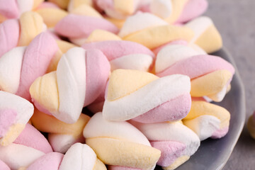 Plate with delicious twisted marshmallows on grey background, closeup