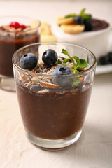 Glass of delicious chocolate pudding with blueberry and almond on white table