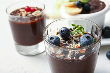Glass of delicious chocolate pudding with blueberry and almond on white table