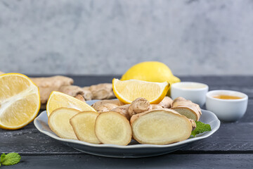 Plate with ginger roots, slices and mint on table