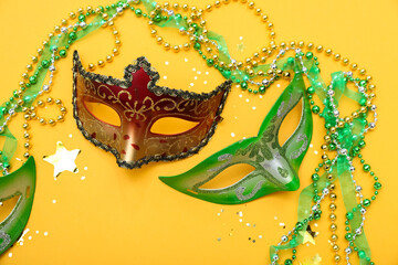 Carnival masks with confetti and beads on yellow background