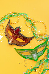 Carnival masks with confetti and beads on yellow background