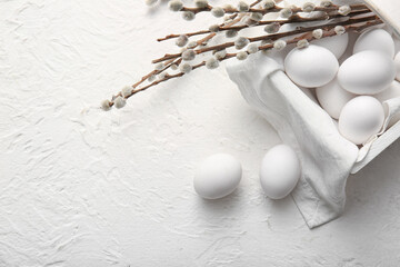 Basket with Easter eggs and willow branches on light background © Pixel-Shot