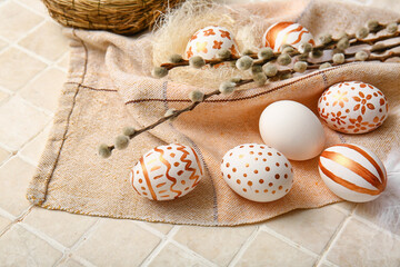 Composition with beautiful Easter eggs and willow branches on light tile, closeup