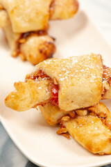Rugelach cookies are made on cream cheese dough with strawberry jam, and mixed nuts topped with cinnamon sugar. 
