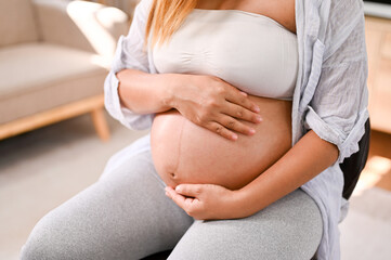 Cropped image of a pregnant woman touching her belly, feeling her baby in her tummy with love