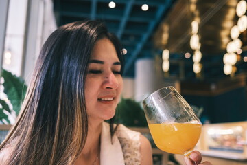 A beautiful woman holding a Glass of an Orange Juice and drink in the Restaurant. Enjoy the moment