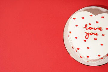 Plate with heart-shaped bento cake on red background. Valentine's Day celebration