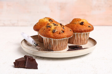 Plate with delicious muffins and chocolate on white table