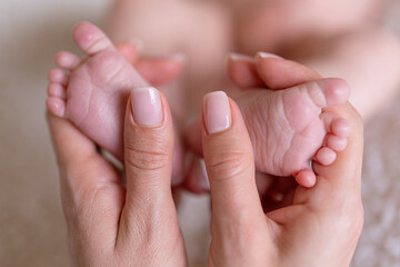 Obraz na płótnie Canvas Newborn or Baby born. Child or kid feet in mother hand. New Mom or mother doing a massage. Barefoot baby. Happy woman. Kid toes. Woman hands love infant feet. Maternity hospital. Happy birthday.