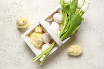 Basket Easter eggs, baby chickens and tulip flowers on grey background
