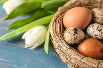 Nest with Easter eggs on blue wooden background, closeup