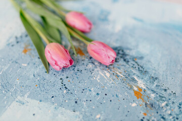 A bouquet of pink fresh tulips lies on a blue and turquoise scenic art background. Abstract blue art background. Fragment of artwork. Contemporary art. Oil paint Valentine's Day Background 